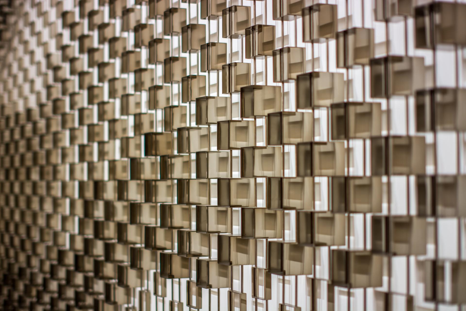 Textured wall featuring geometric surface design, showcasing light and shadow play, reflecting Giles Miller's innovative approach to art.