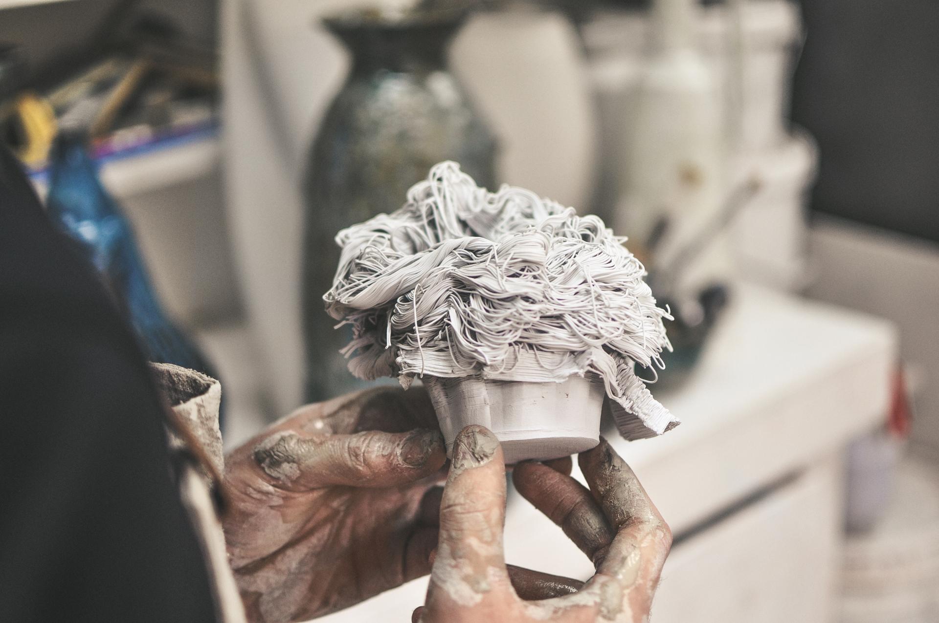Ceramic artist Ryan Barrett holds a textured clay sculpture, showcasing his innovative approach to pottery and creativity.