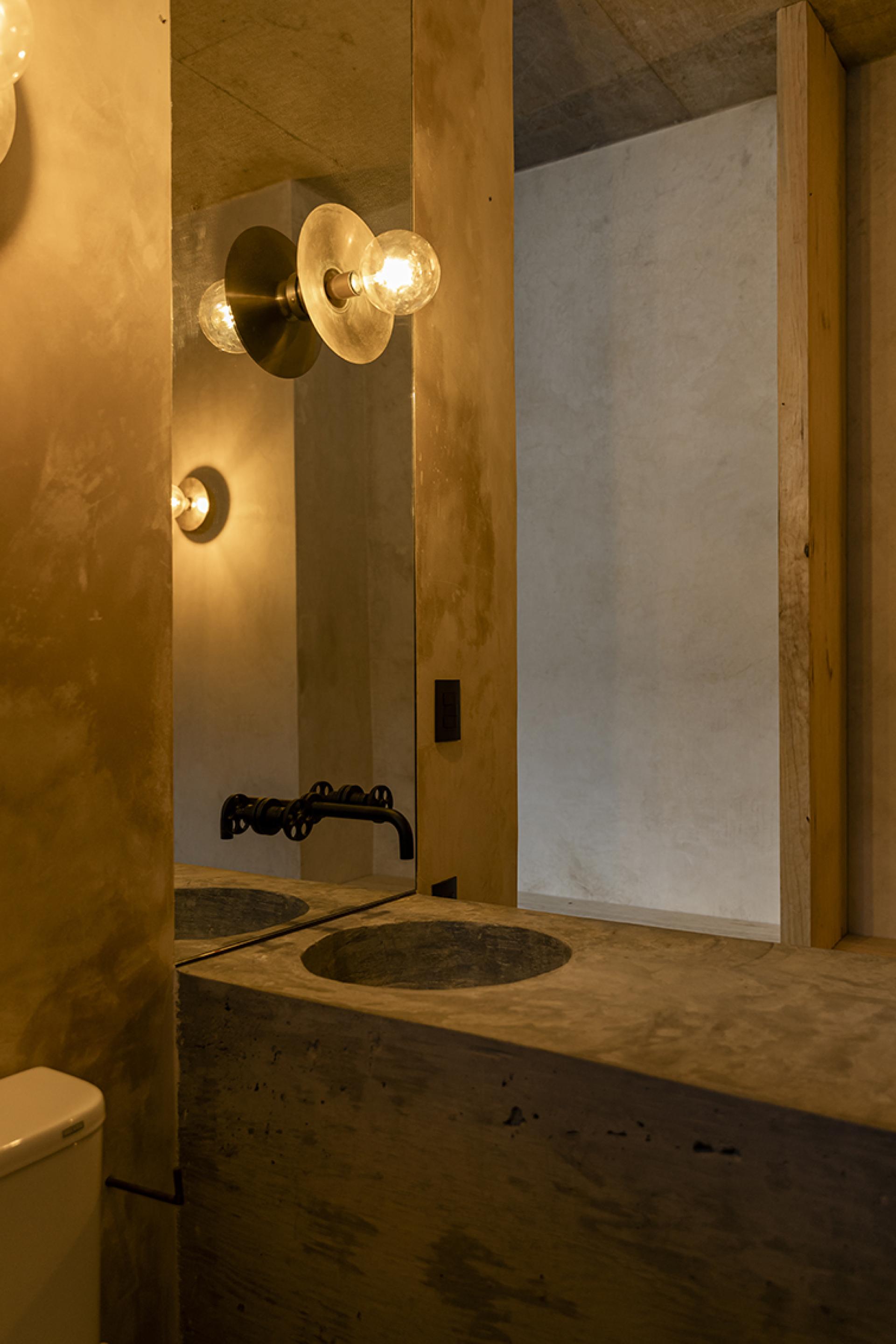 Stylish modern bathroom with concrete sink, elegant lighting, and minimalist design in Avocado House, Mexico.