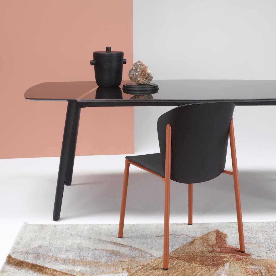 Elegant black table inspired by cuttlefish bone, paired with a sleek chair and decorative accessories against a minimal backdrop.
