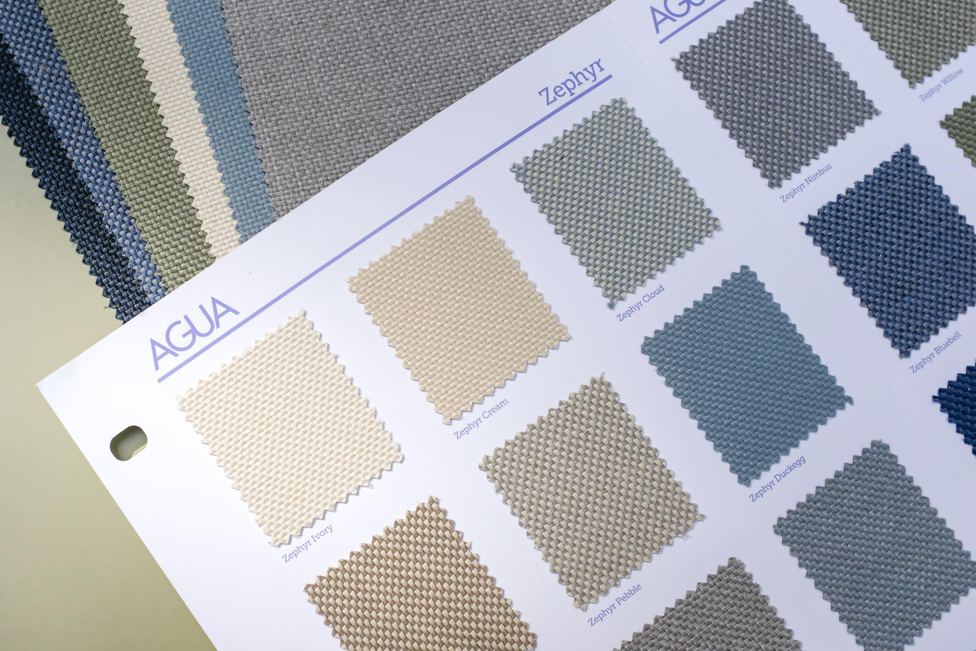 Swatches of Agua's Zephyr two-tone woven fabric showcase various colors, highlighting its textured design for indoor and outdoor use.