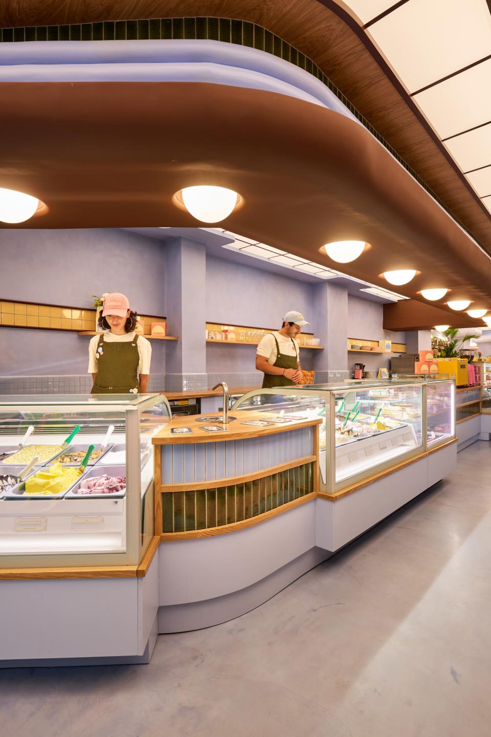 Stylish ice cream parlour with Art Deco-inspired decor and staff in playful uniforms serving colorful frozen treats.
