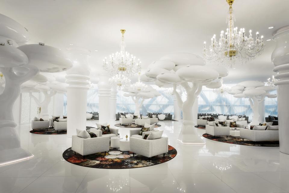 Luxurious lounge at Mondrian Doha featuring white tree sculptures, elegant chandeliers, and stylish seating arrangements designed by Marcel Wanders.