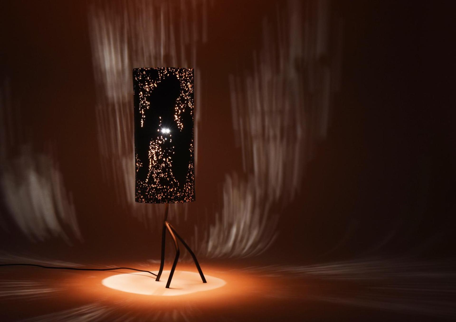 Stylish lamp with intricate cut-outs casting artistic light patterns, showcasing contemporary design from Dutch Design Week 2023.