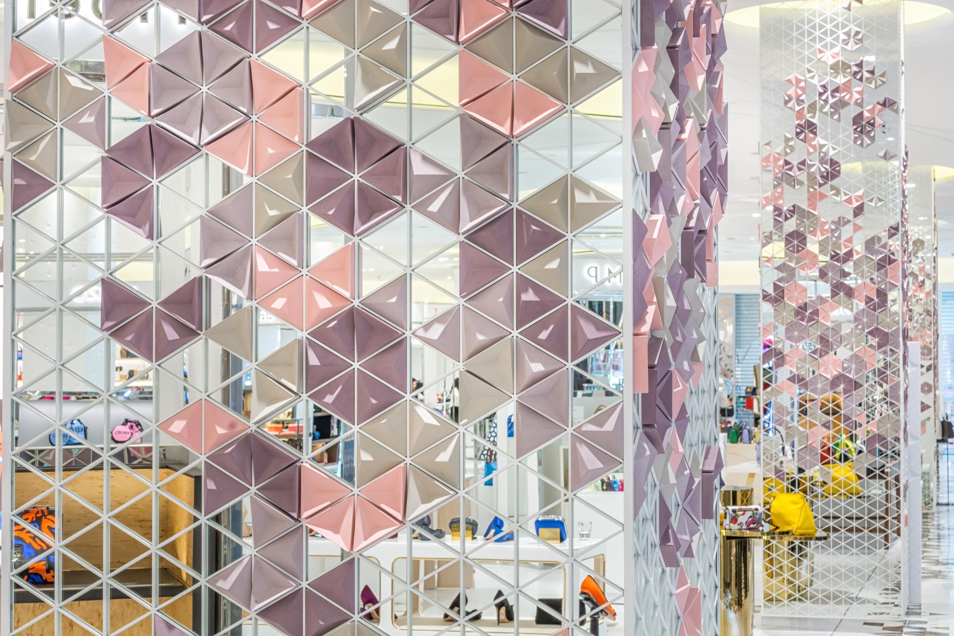 Vibrant geometric surface design featuring reflective and textured elements, showcasing Giles Miller's innovative art in a retail setting.
