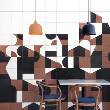 Bold geometric wall design with contrasting colors, modern furniture, and stylish pendant lighting in a vibrant interior space.