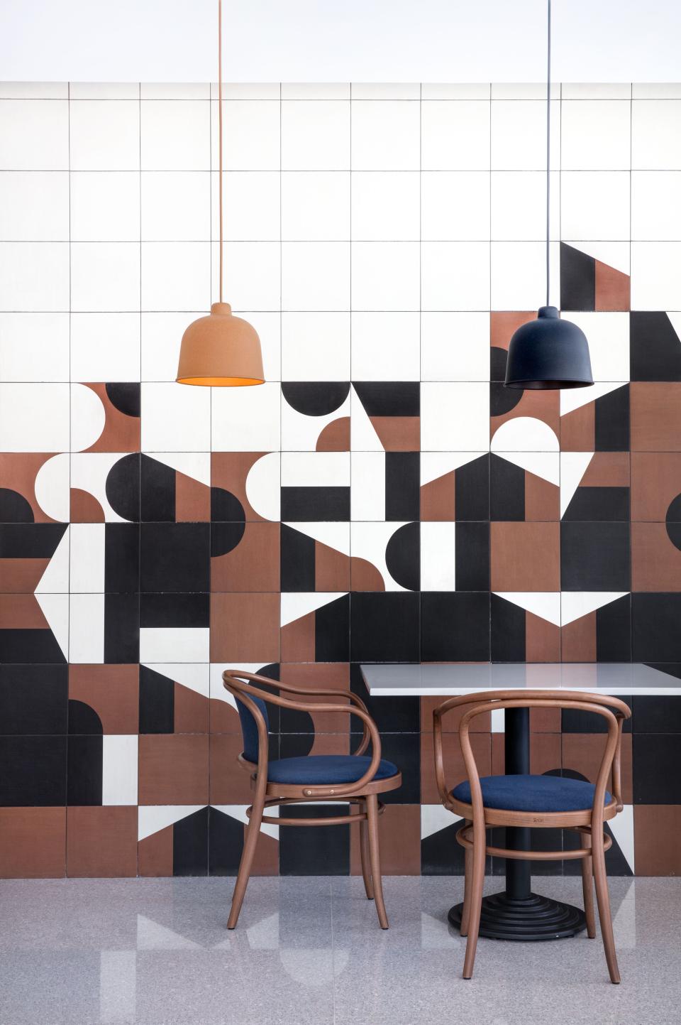 Bold geometric wall design with contrasting colors, modern furniture, and stylish pendant lighting in a vibrant interior space.