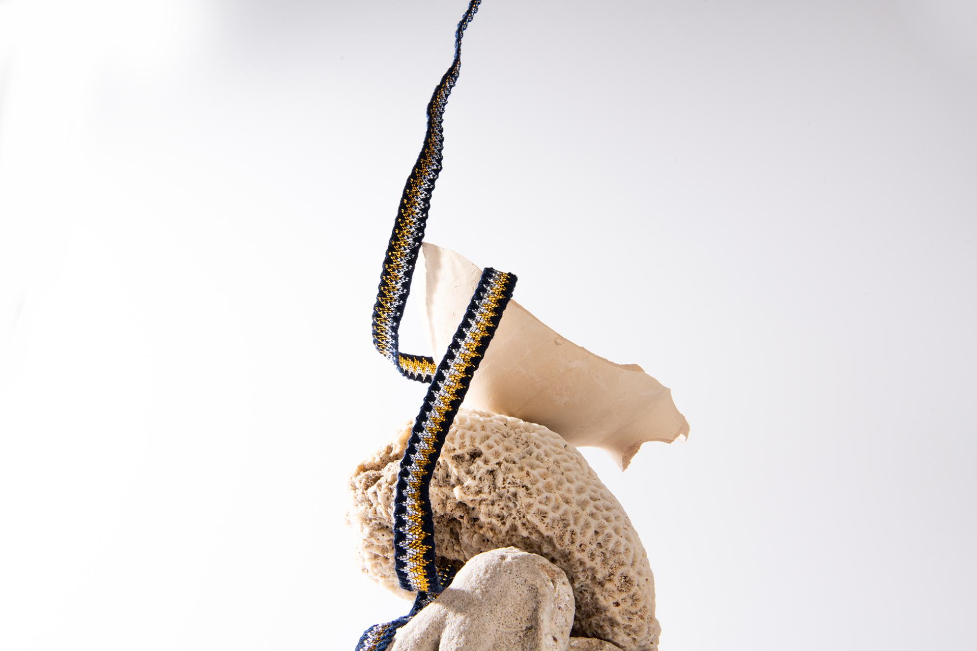 Artistic display featuring a textured stone sculpture adorned with colorful fabric, symbolizing innovation in contemporary design.