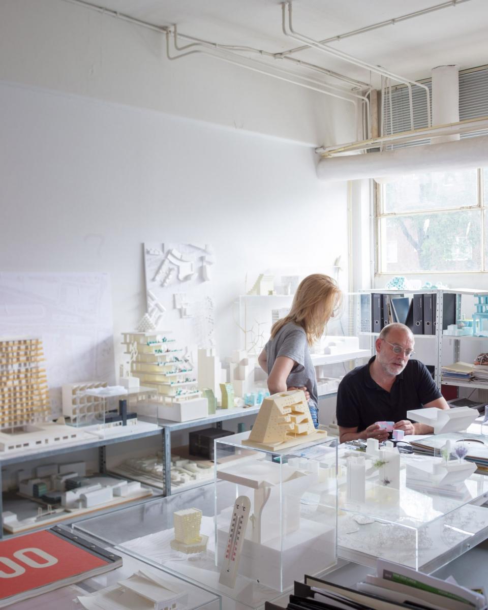 Architects collaborating in a bright studio, surrounded by architectural models and design plans, showcasing innovative Dutch architecture.