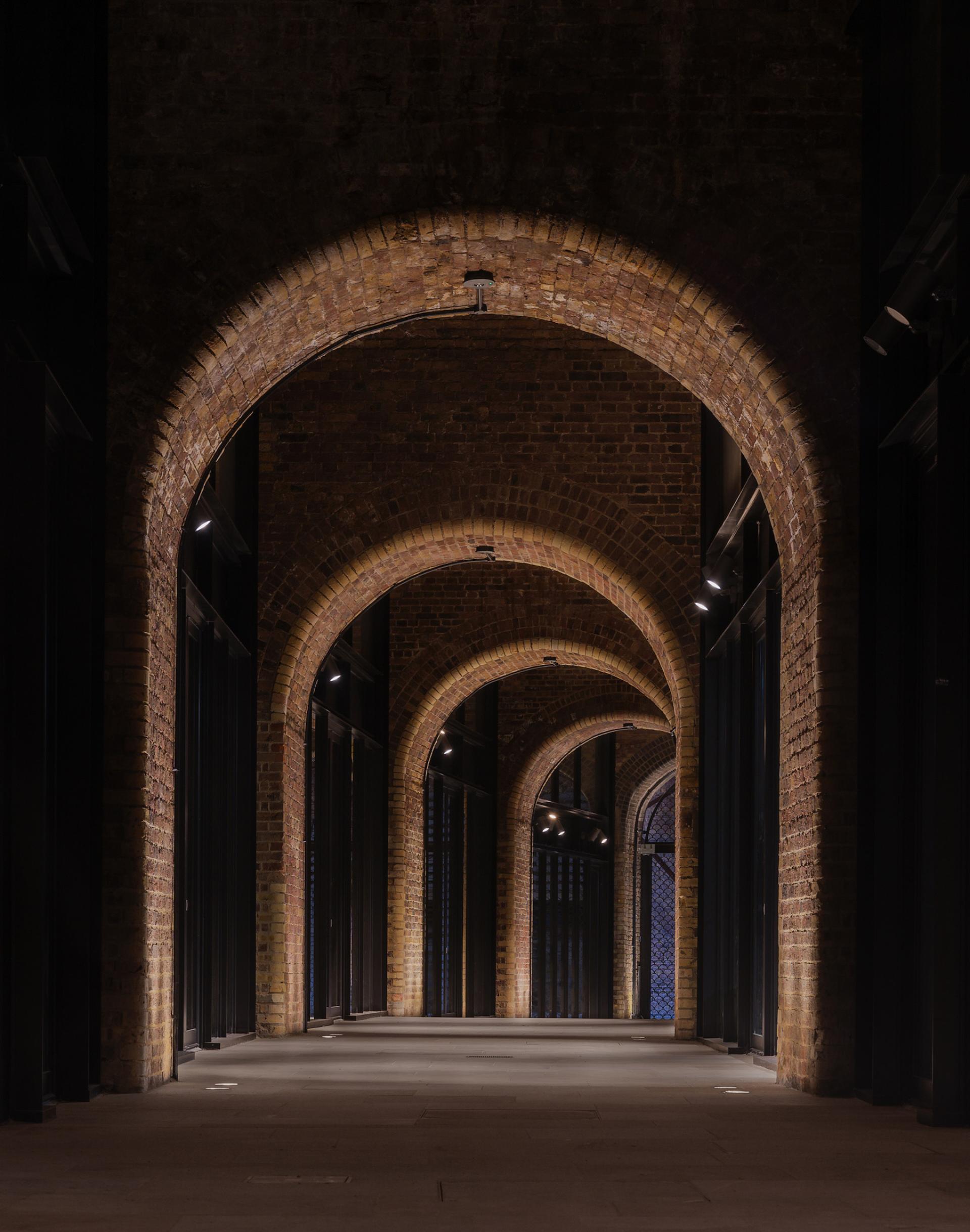 Illuminated brick arches create a stunning architectural walkway at Borough Yards, enhancing the cultural experience in London.