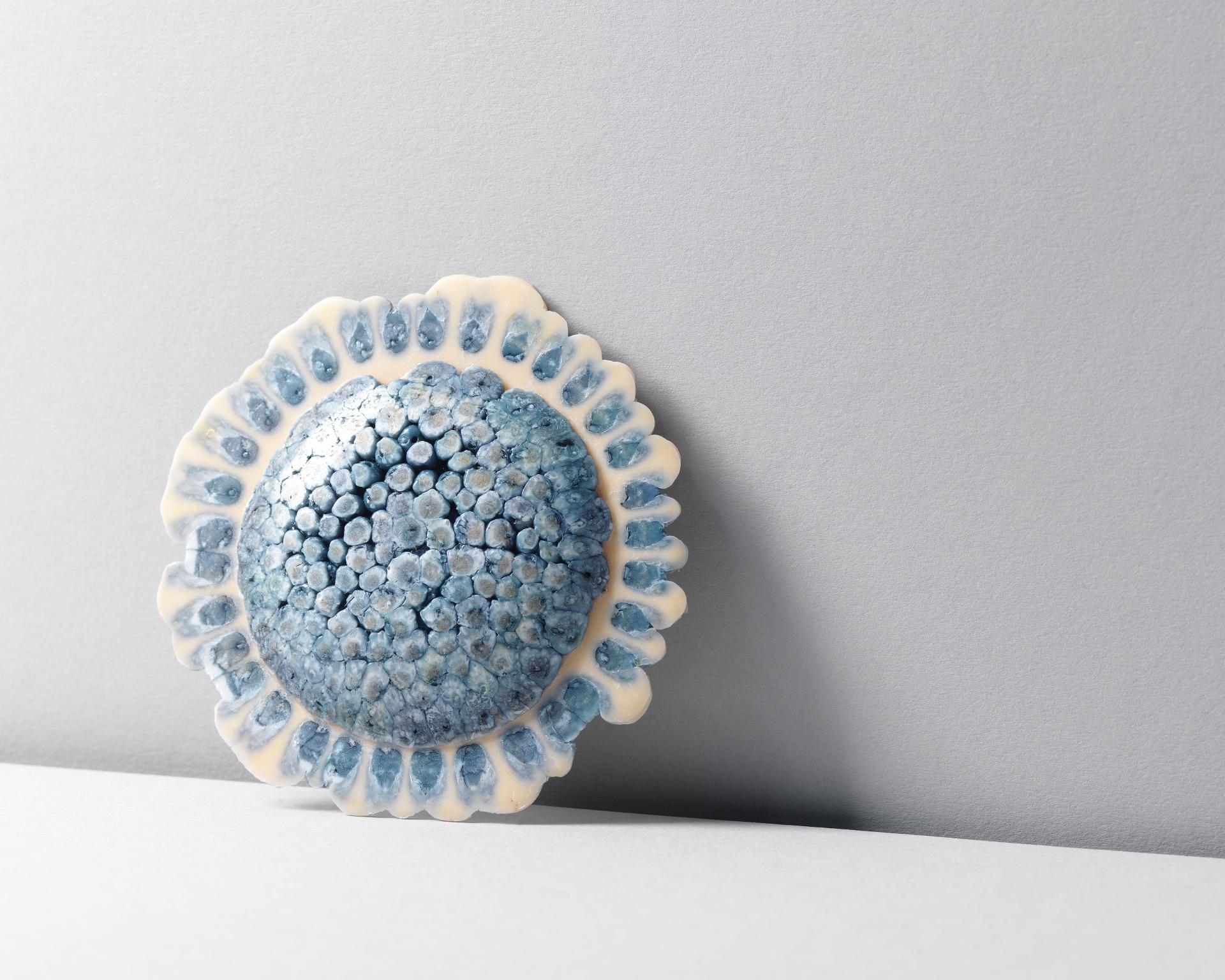 Ceramic design piece featuring intricate blue textures, showcasing sustainable materiality at New Designers event.