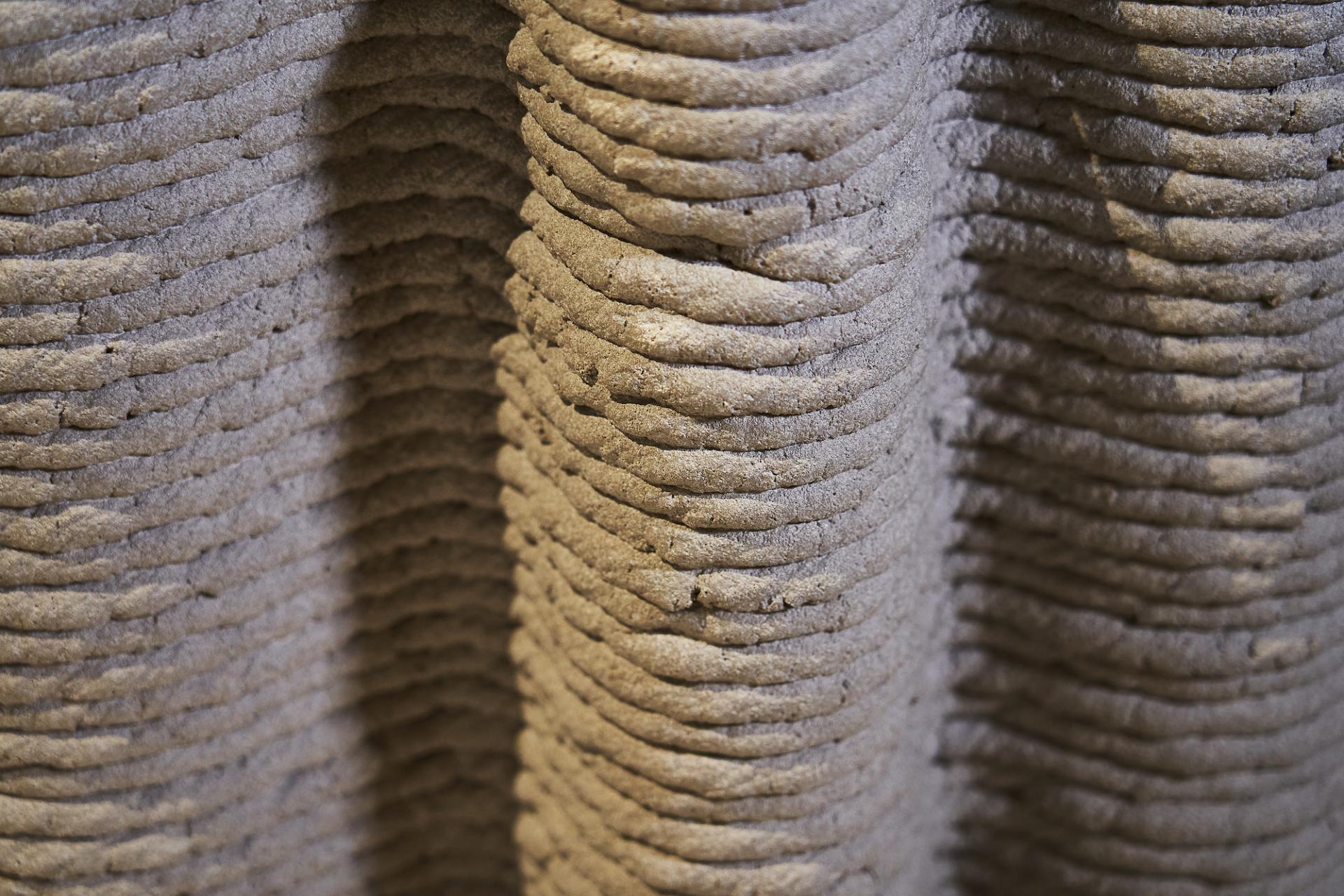 Close-up view of textured 3D-printed concrete layers, showcasing innovative materials used in sustainable construction practices.