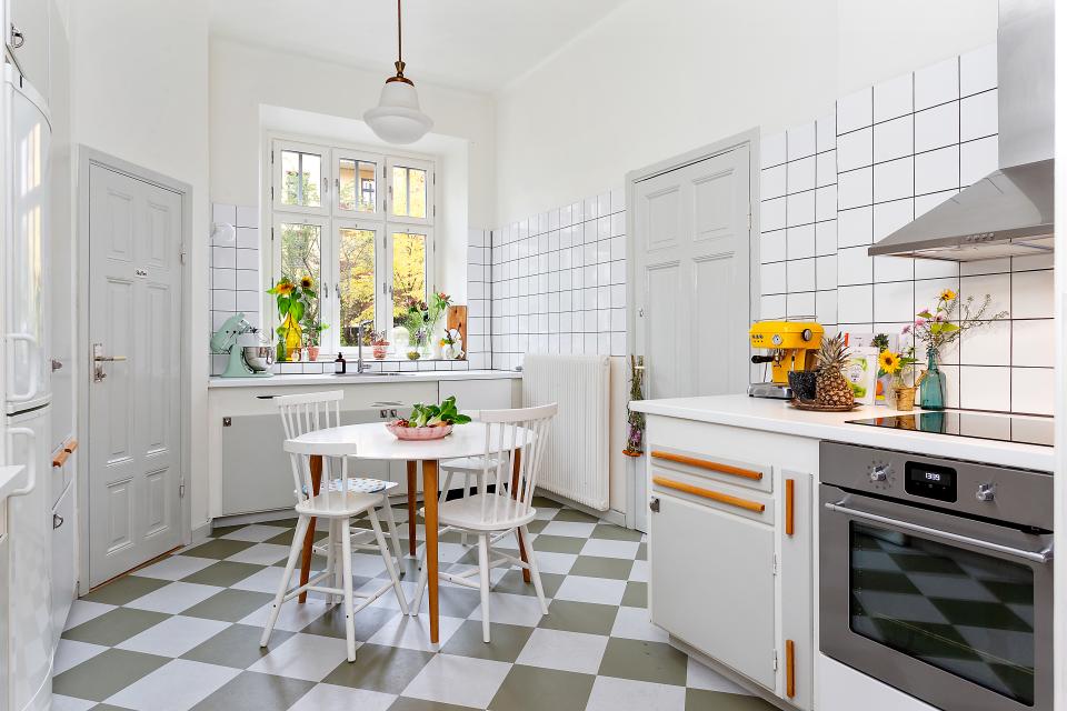 Bright Scandinavian kitchen showcasing minimalist design, featuring a round table, tiled walls, and modern appliances.