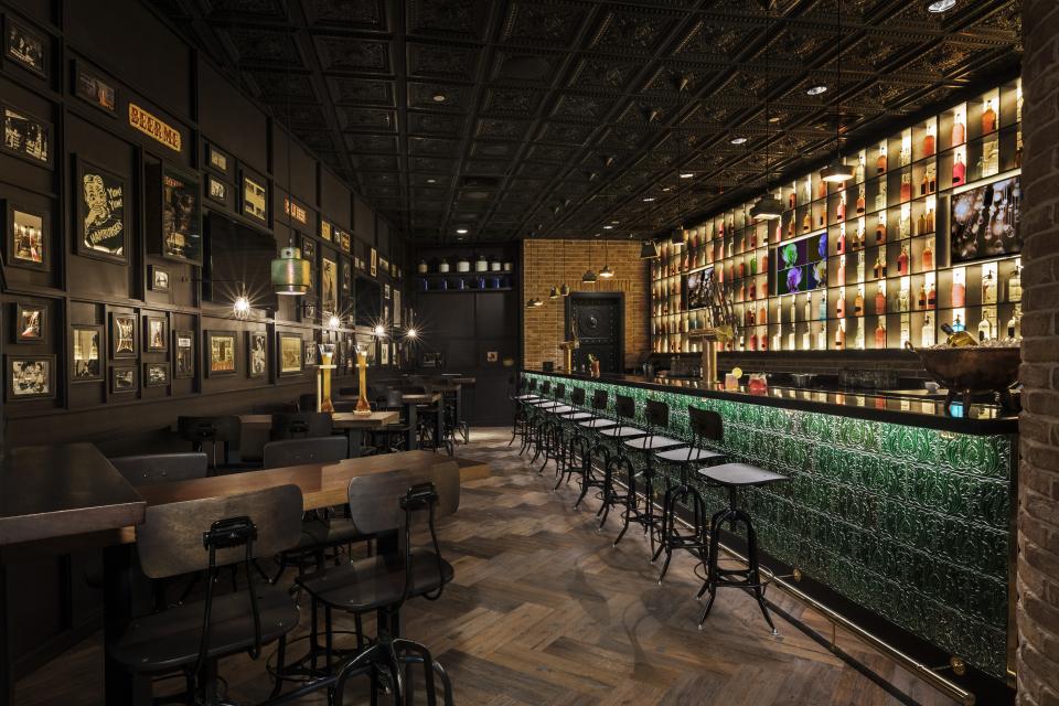 Stylish bar interior at Mondrian Doha, featuring eclectic decor, illuminated drink shelves, and intricate ceiling design.