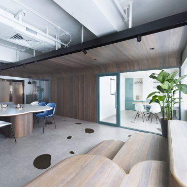 Modern paediatric clinic interior featuring a welcoming design with a round table, colorful chairs, and green plants.