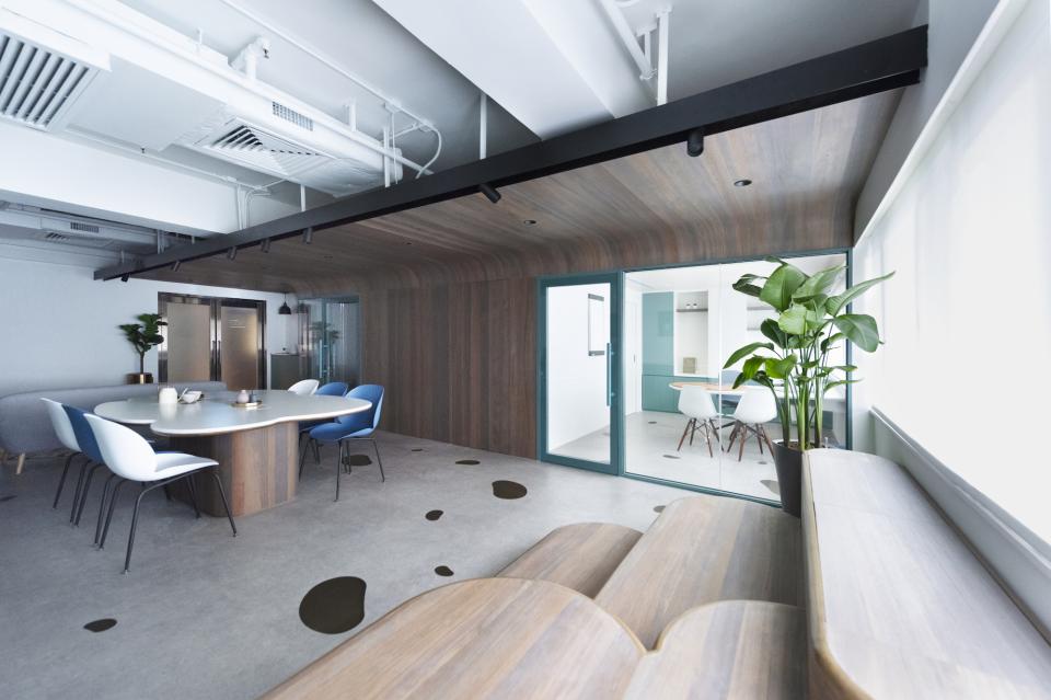 Modern paediatric clinic interior featuring a welcoming design with a round table, colorful chairs, and green plants.