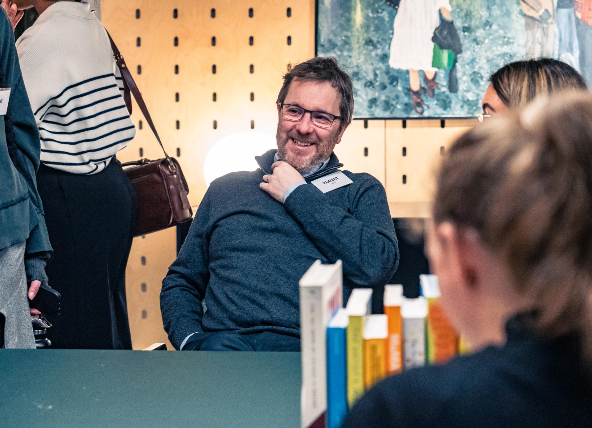 Engaged discussion at a networking event focused on achieving Net Zero sustainability goals, with participants and books visible.