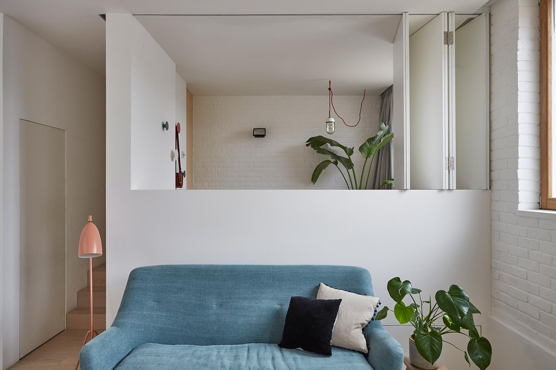Stylish interior featuring a blue sofa, modern decor, plants, and natural light in a Hackney mews house.