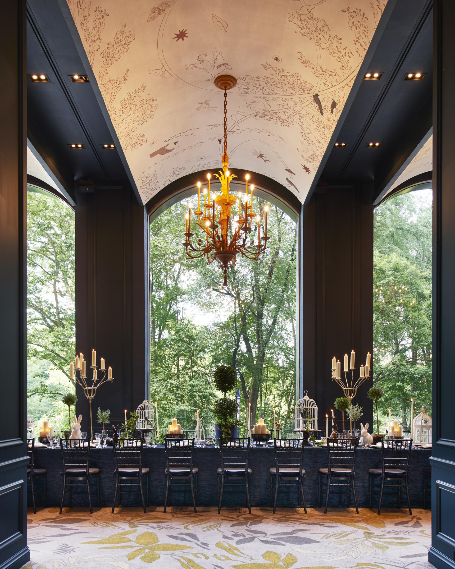 Elegant dining space at Park Lane New York, featuring a grand chandelier and lush greenery views.