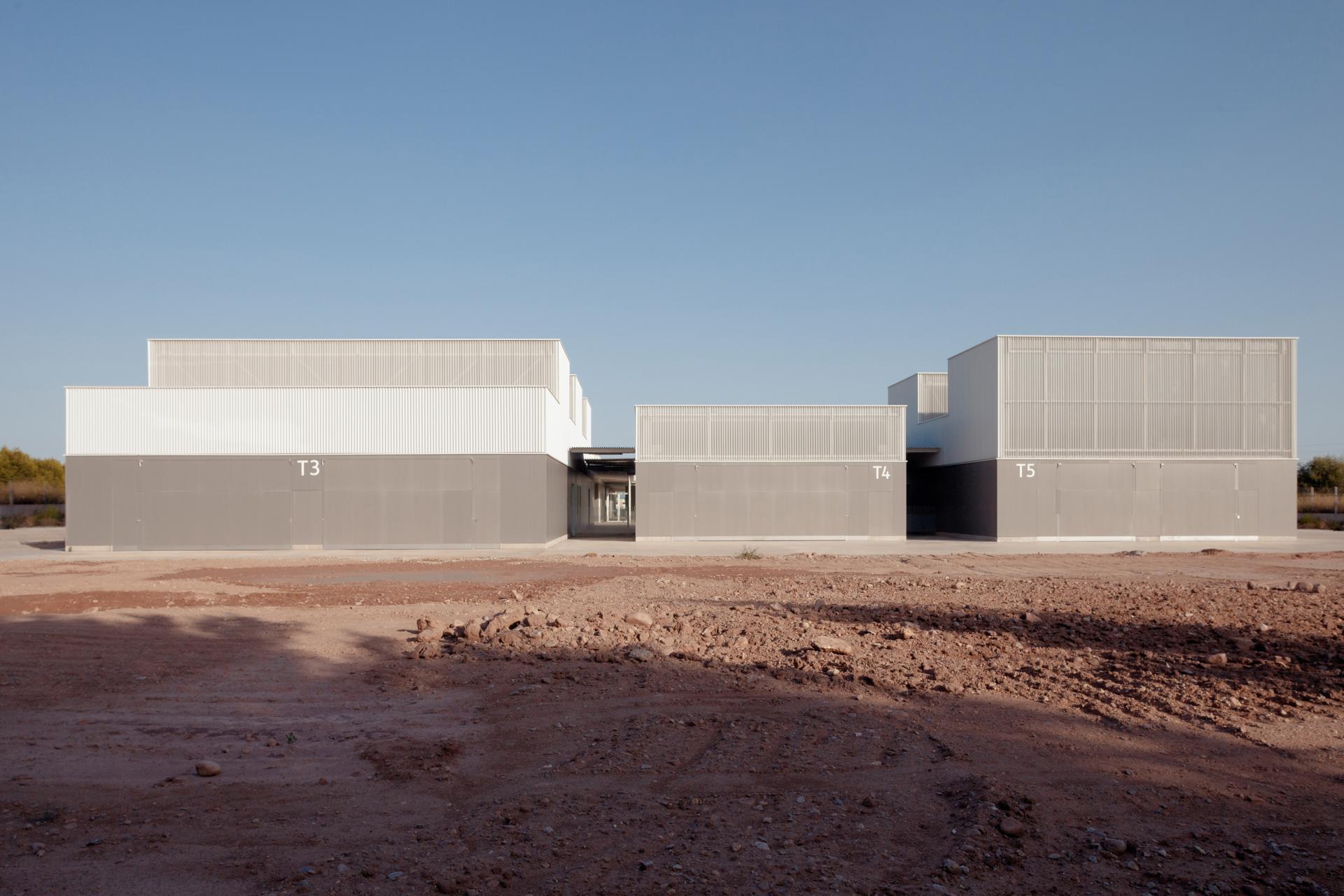Modern architectural buildings showcasing innovative Spanish ceramic design against a clear blue sky in an open landscape.