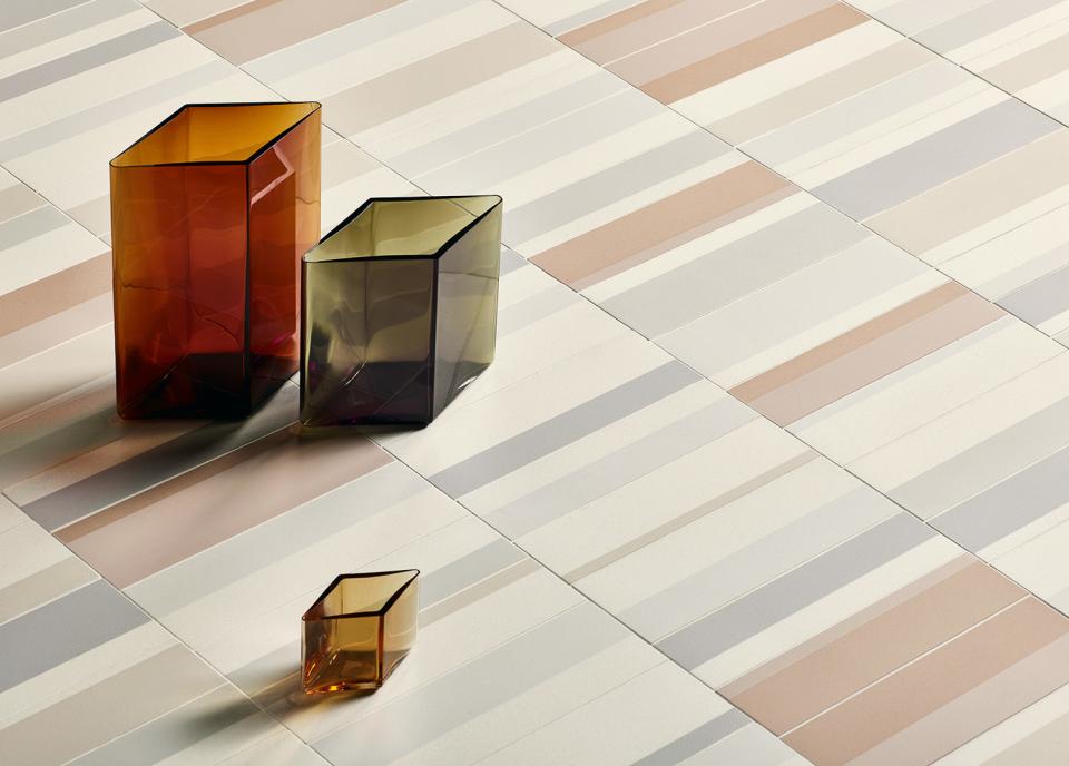 Elegant geometric glass vases displayed on a stylish tile floor featuring the new Piano tile collection by Domus.