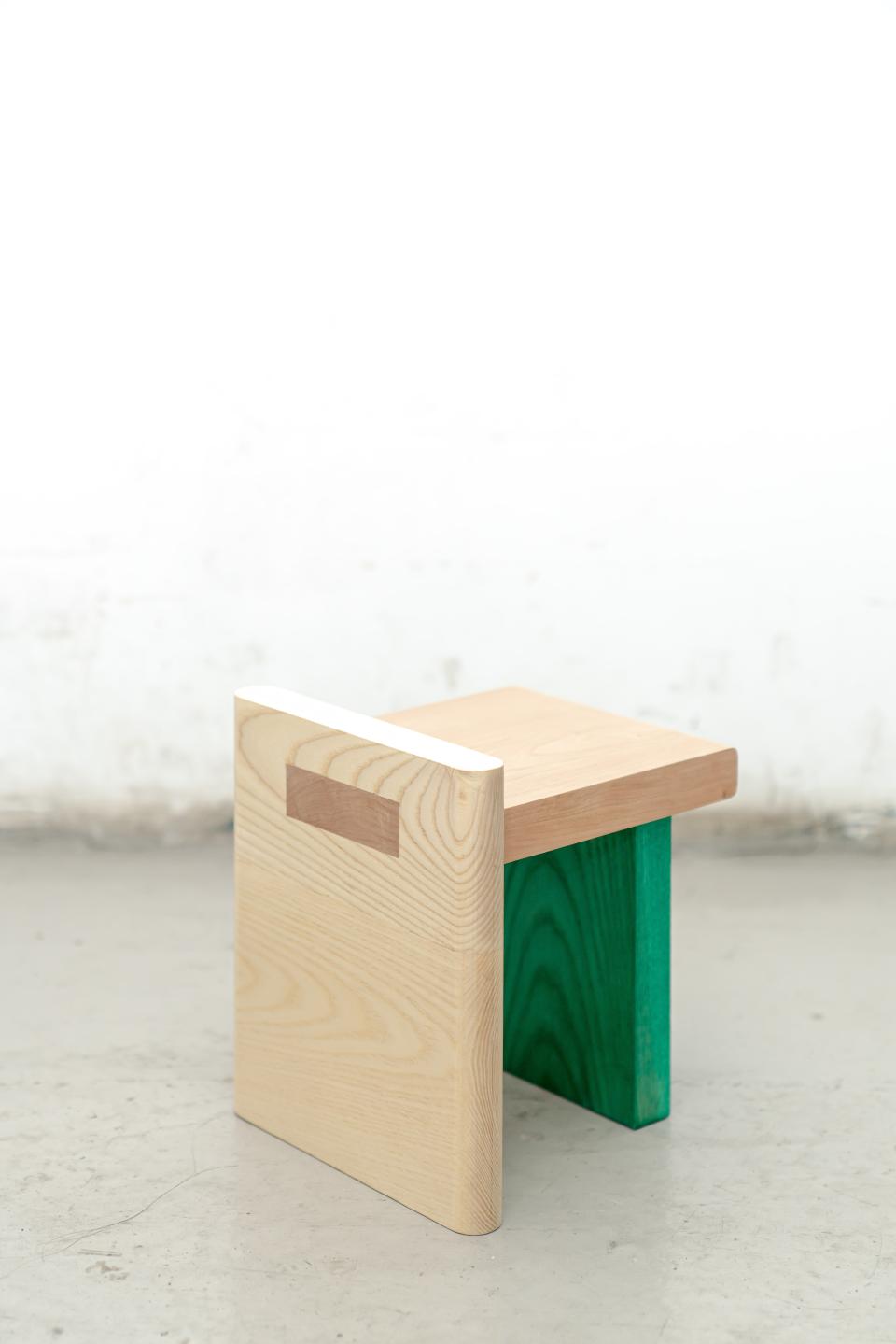 Mini-stool featuring a light wood finish with a green accent, showcasing versatile and adaptable design in furniture craftsmanship.