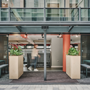 Modern student accommodation entrance at The Refinery, featuring indoor greenery and contemporary design elements.
