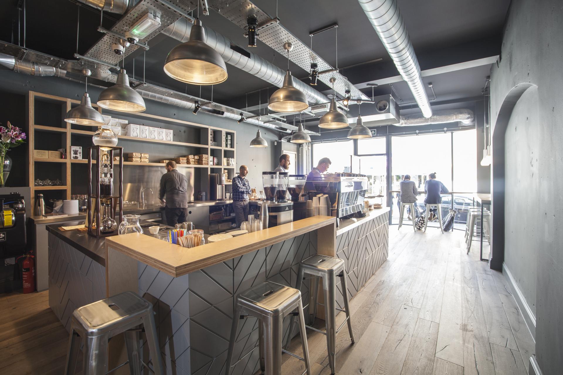 Modern coffee shop interior featuring baristas, sleek design, and a view of customers enjoying specialty coffee.