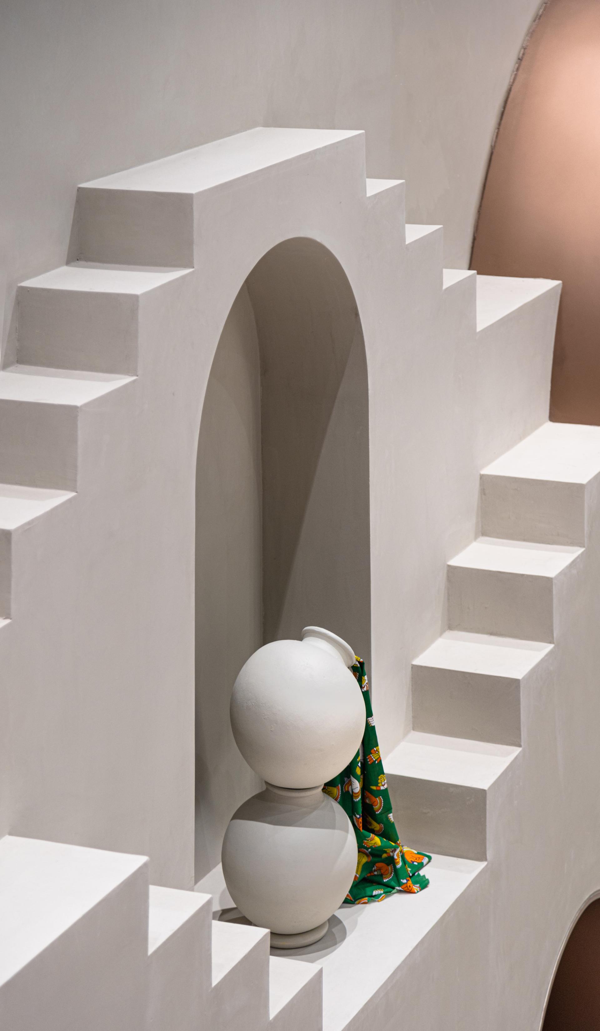 Stylish white stone sculpture sits among steps and arches inspired by Rajasthani architecture at Jaipur Rugs' Dubai showroom.