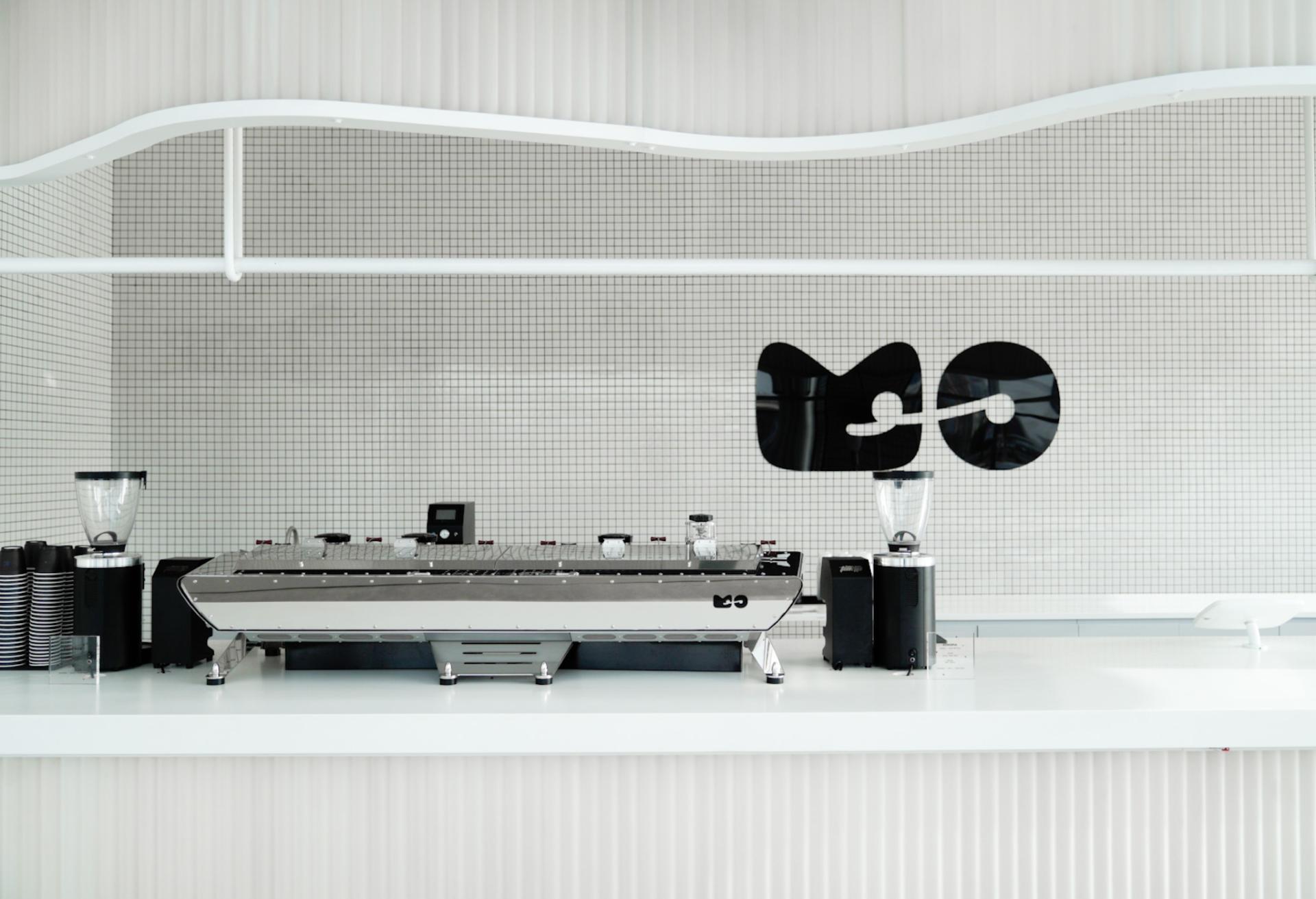 Sleek espresso bar counter at MO, featuring modern coffee equipment and a minimalist black and white design.