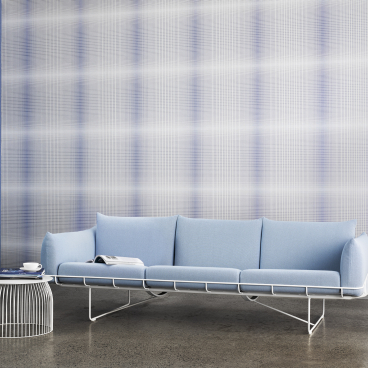 Cosy blue sofa against a stylish plaid acoustic wall, showcasing modern design and innovative sound-absorbing solutions.