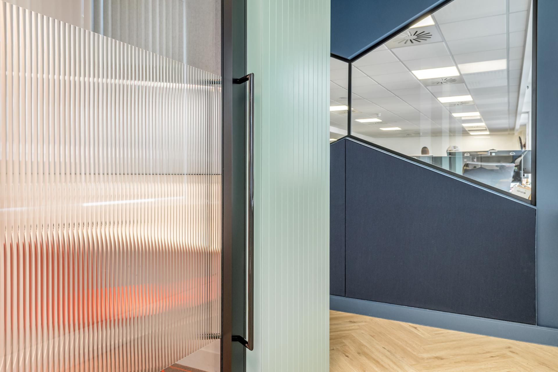Modern office interior featuring sleek glass partitions and stylish geometric design elements at Lexis Nexis Tech Hub.