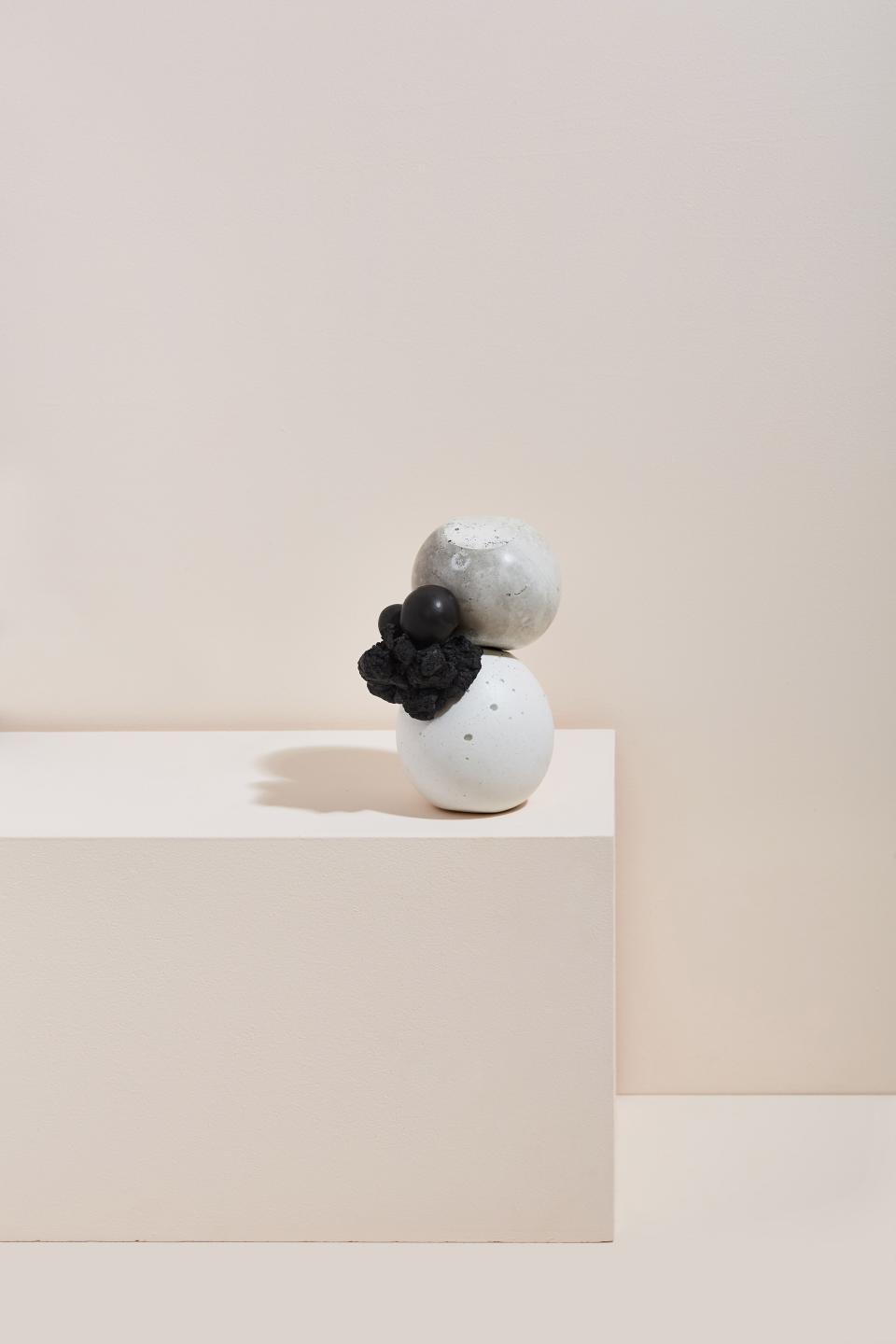 Sculptural arrangement of textured materials, featuring spherical forms in white and gray, enhanced by a black organic element.