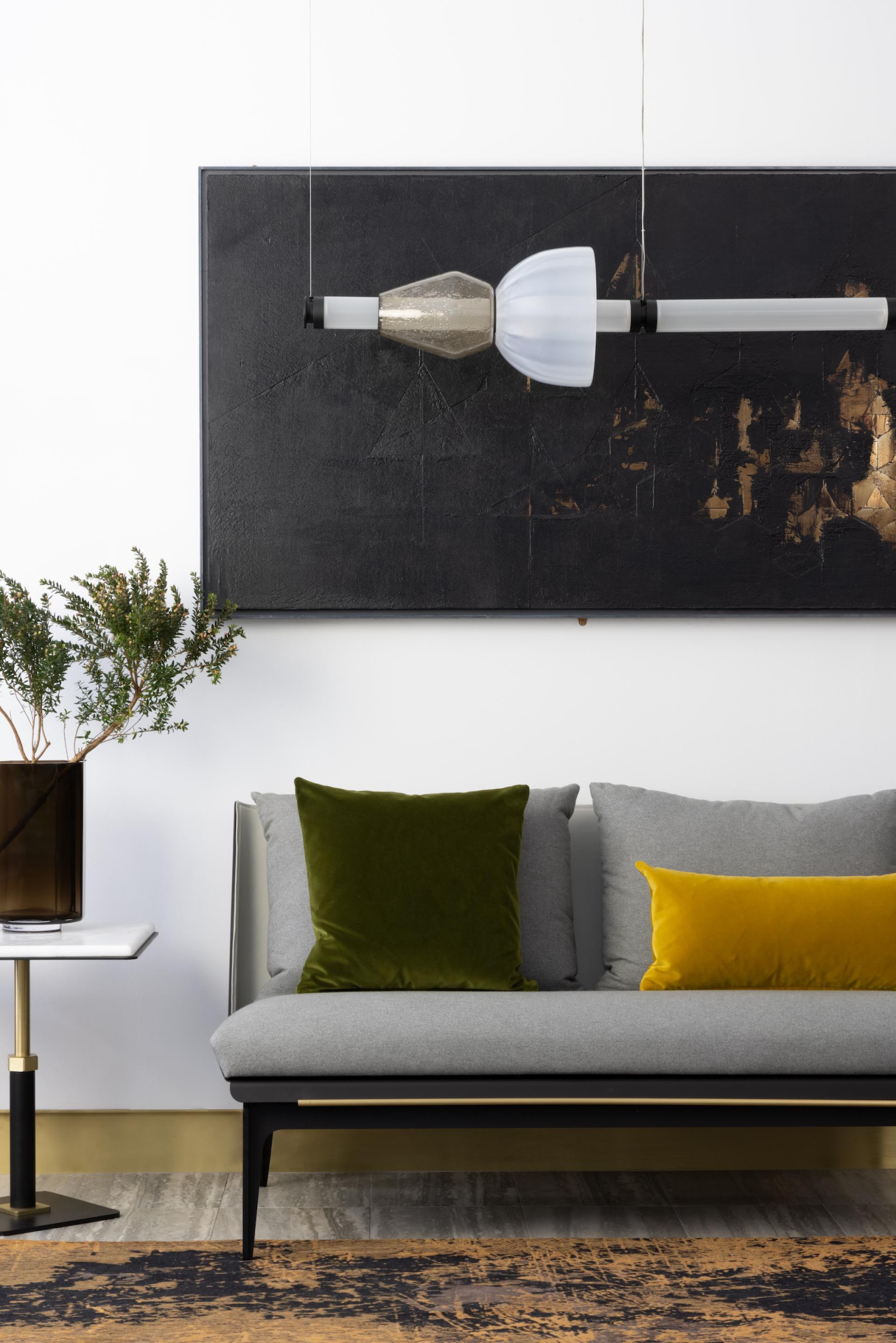 Luna Kaleido lighting fixture suspended above a modern sofa with colorful pillows in an elegant interior setting.