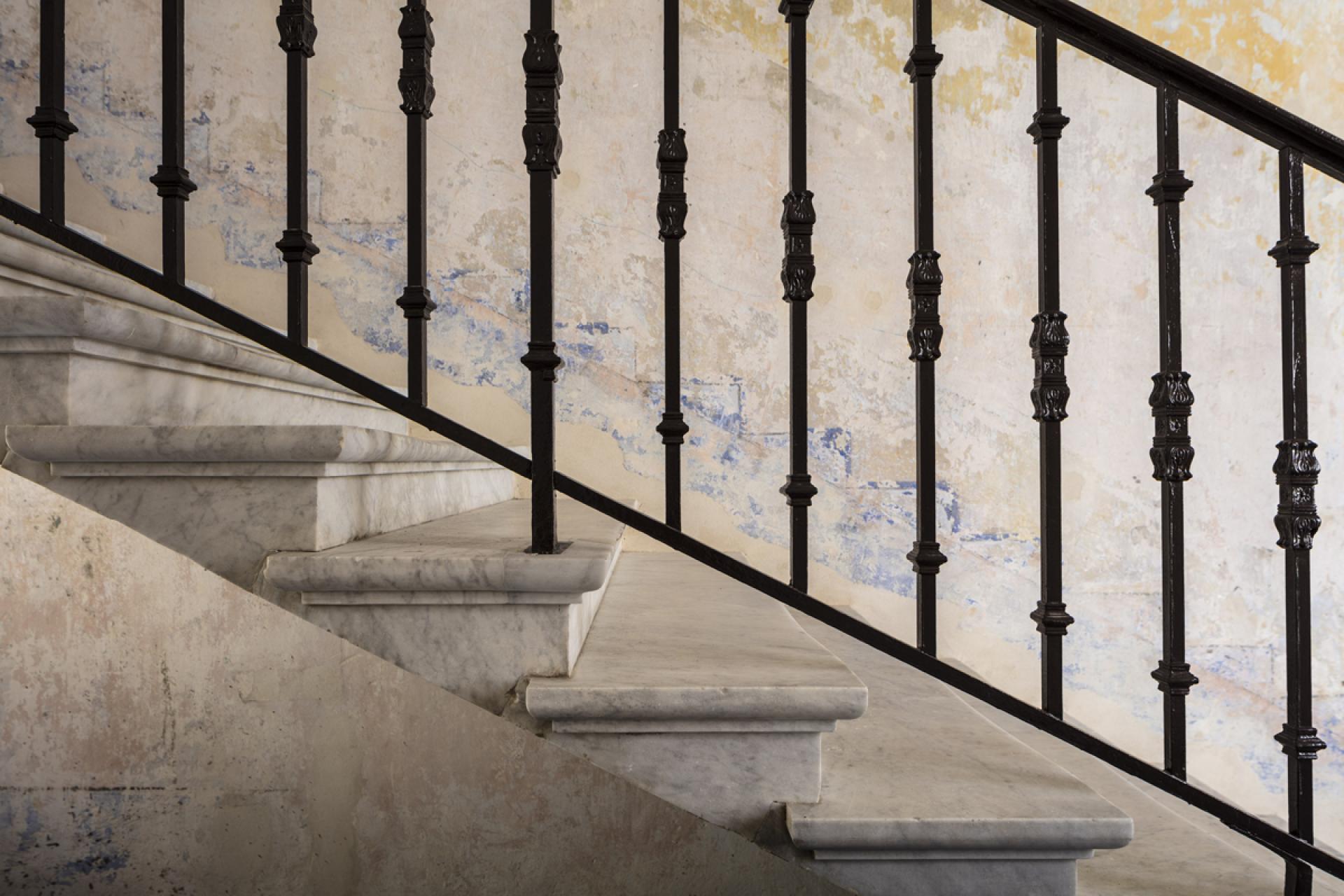 Minimalist staircase design featuring elegant marble steps and ornate black railings at The Jaffa, Tel Aviv.