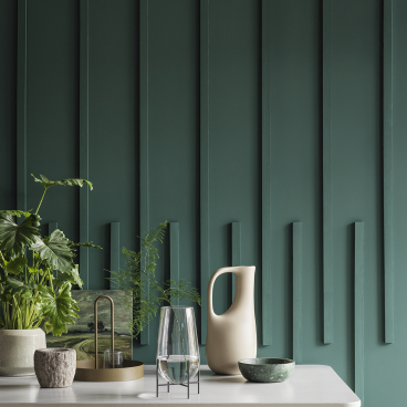 Stylish tabletop arrangement featuring greenery, modern ceramics, and a textured teal wall, highlighting SS22 color trends from Crown Paints.