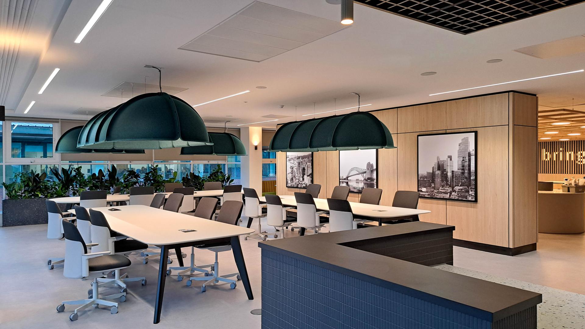 Modern workspace designed for Conferma, featuring large tables, stylish green lighting, and urban artwork.