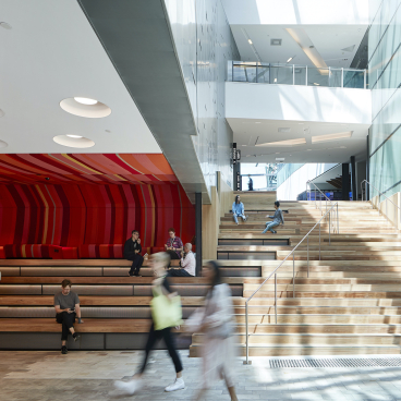 Modern interior of ACMI in Melbourne featuring vibrant seating areas and an expansive staircase with visitors.