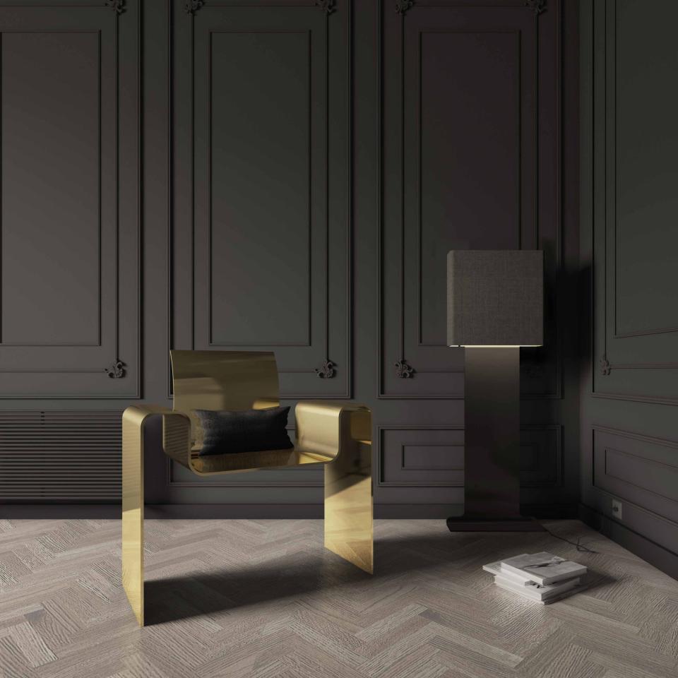 Sleek gold chair with a black cushion beside a modern lamp in an elegant minimalist interior setting.