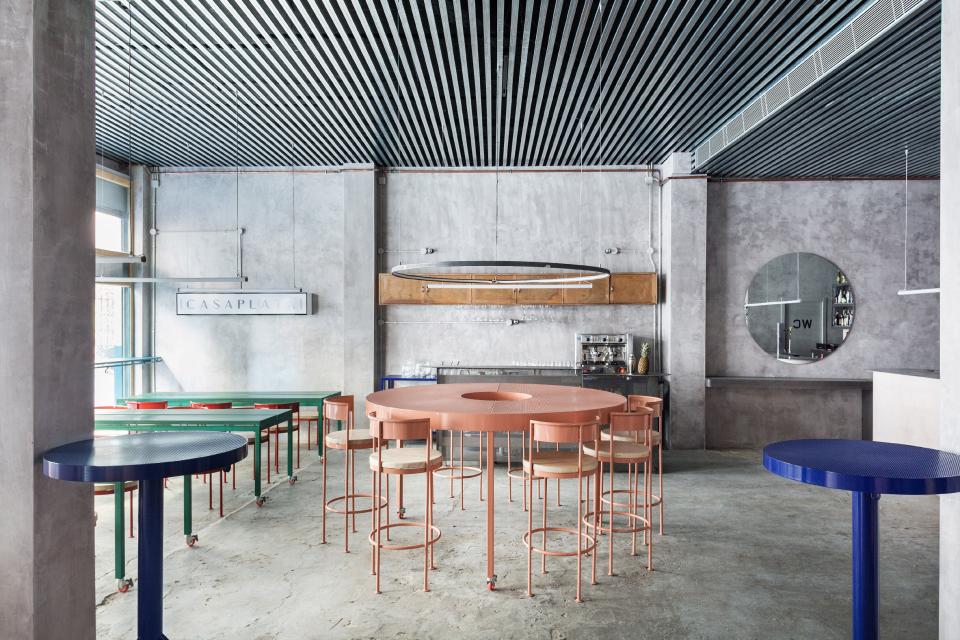 Interior of a Seville restaurant featuring concrete walls, colorful furniture, and modern lighting design by Lucas y Hernández-Gil.