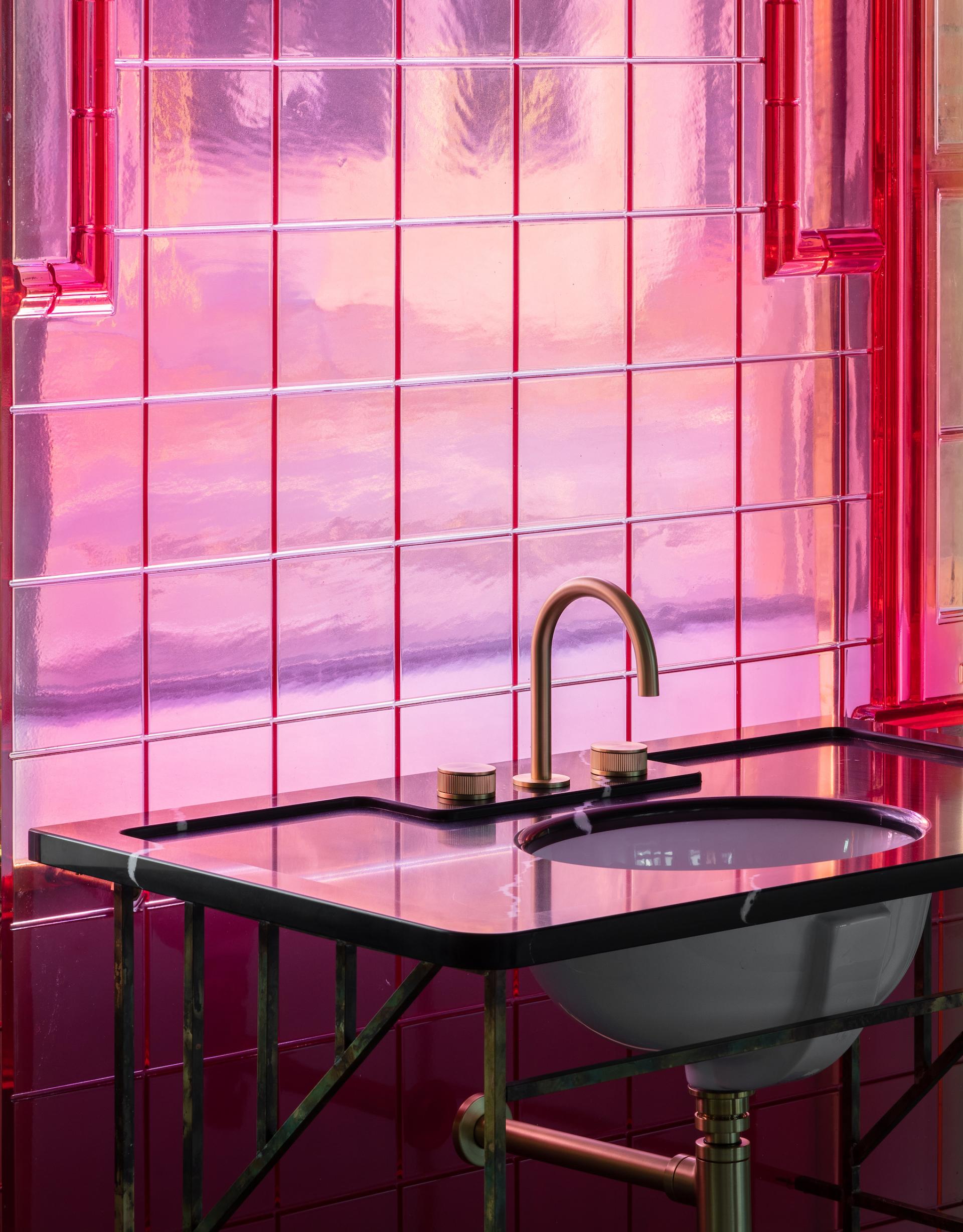 Innovative bathroom sink design with sleek faucet and vibrant pink tiled backdrop in Holloway Li's Clerkenwell showroom.