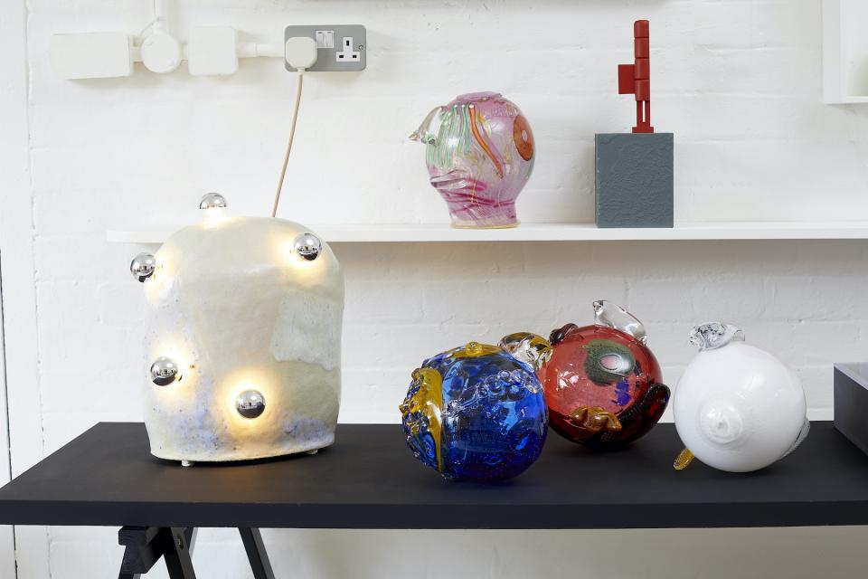 Colorful glass sculptures and a unique light fixture displayed on a shelf at House on Mars during Collect 2021 art fair.