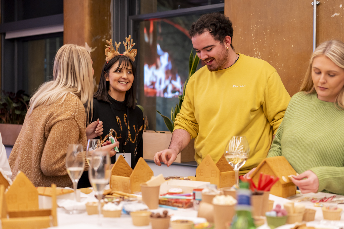 Creative celebration at Material Source Studio, featuring people making gingerbread houses and enjoying festive decorations.