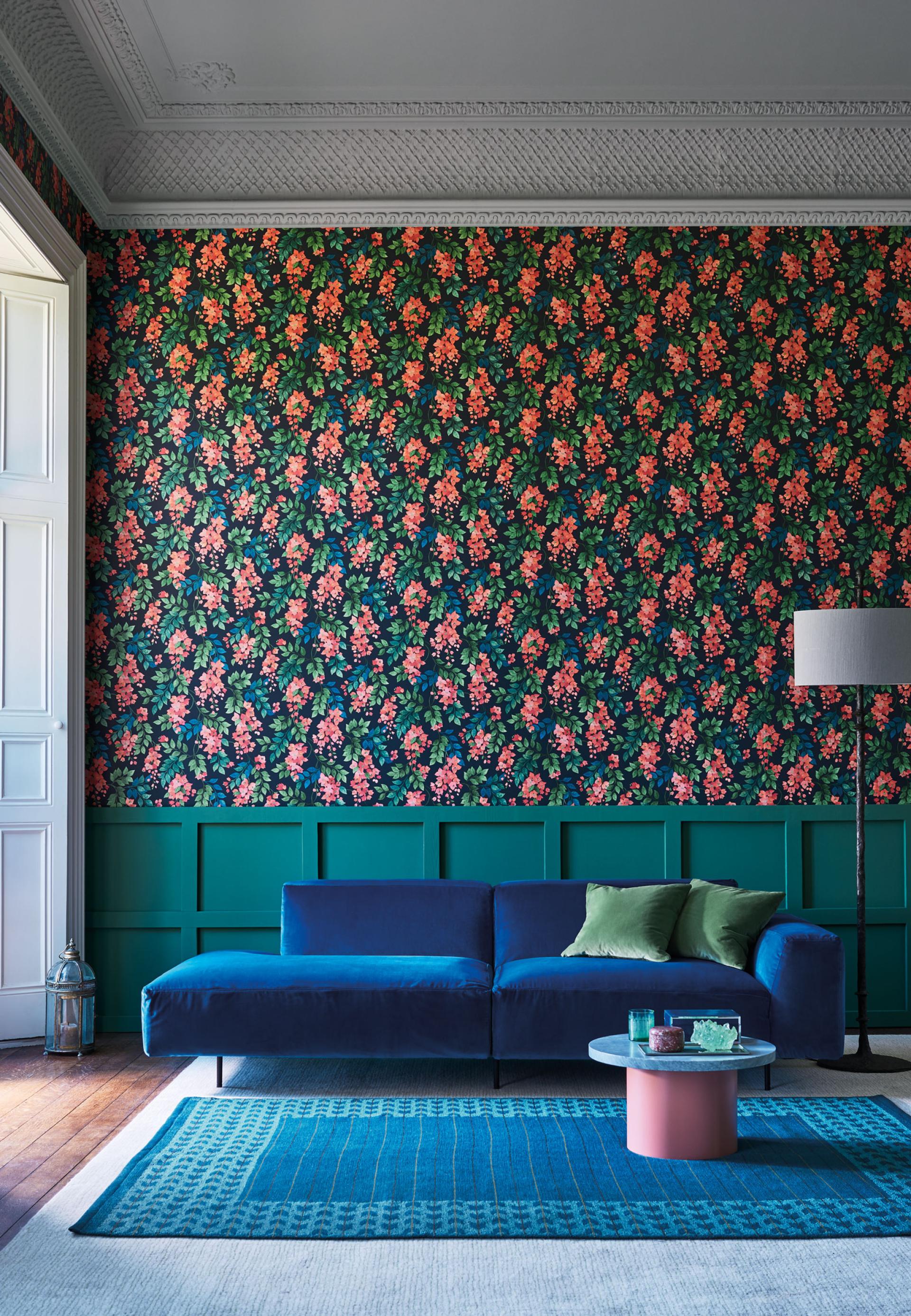 Vibrant wallpaper featuring floral patterns complements a stylish blue sofa and modern decor in a chic interior setting.