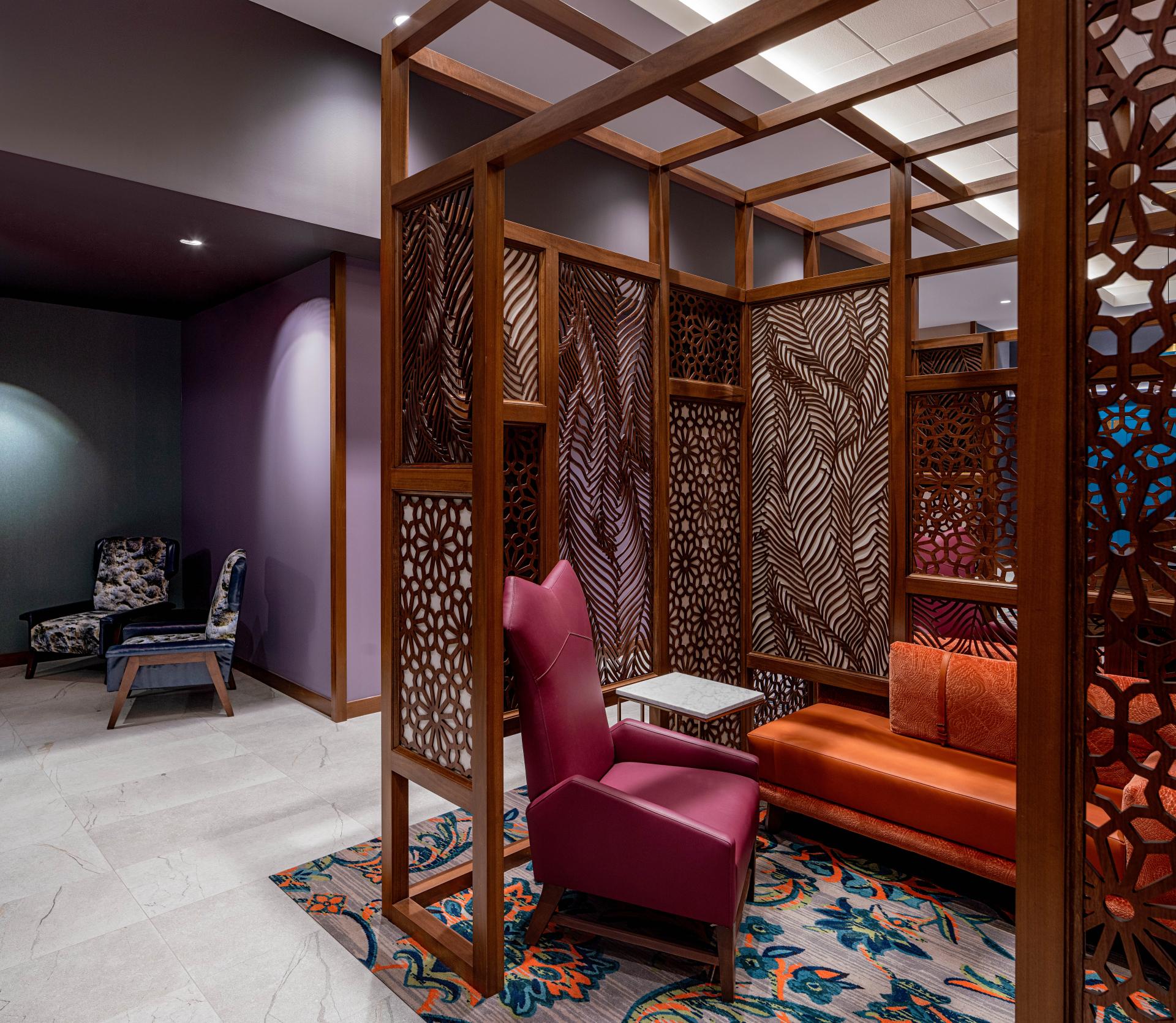 Stylish seating area featuring vibrant colors and geometric wooden partitions at Hyatt House, Tampa's modern interior design.