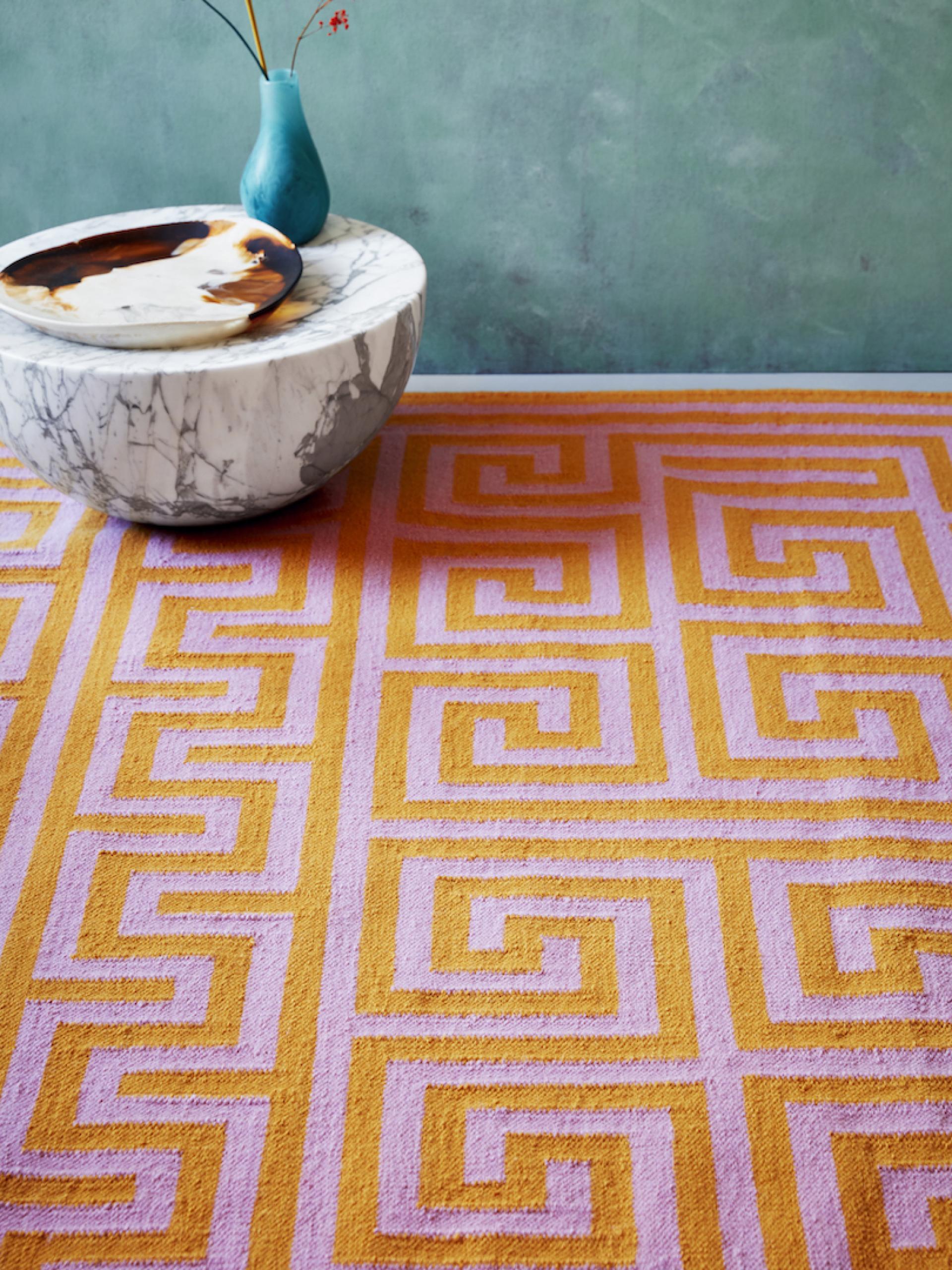Mediterranean-inspired rug designed by Adam Nathaniel Furman, featuring a vibrant geometric pattern in pink and yellow tones.