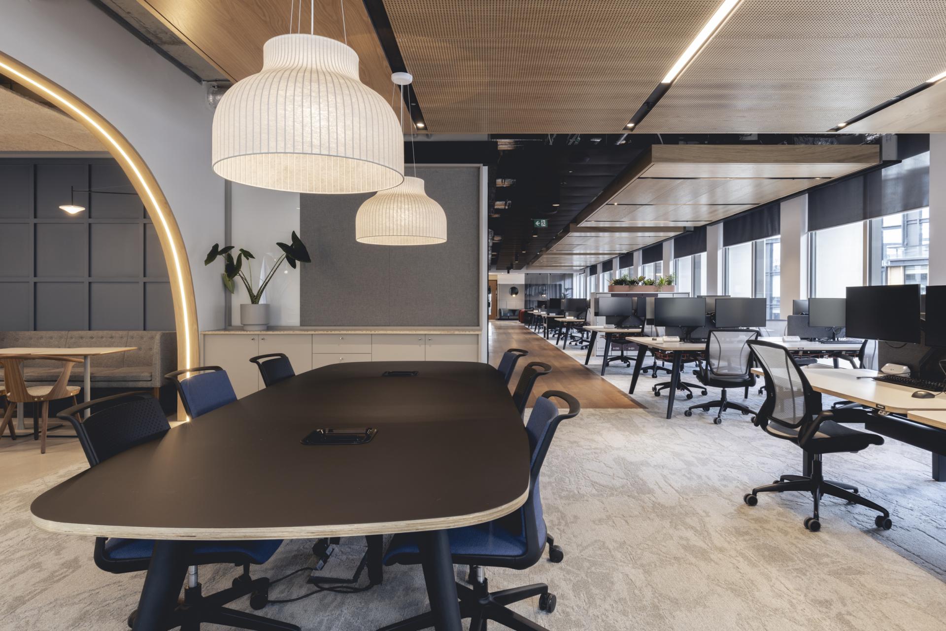 Contemporary office interior featuring a large meeting table, stylish lighting, and workstations, exemplifying Ekho Studio's creative space.