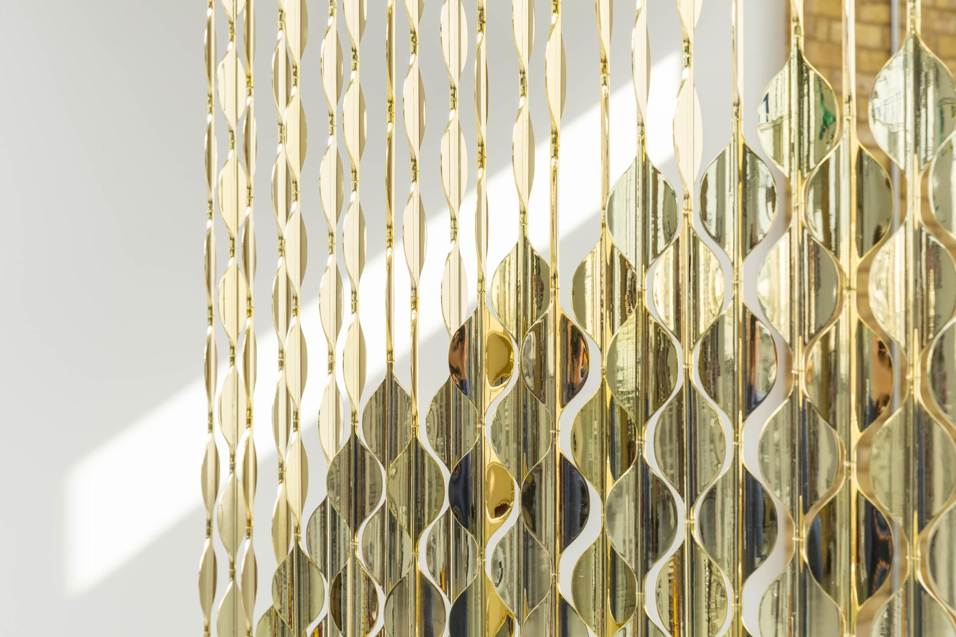 Reflective golden surfaces arranged in a decorative pattern, showcasing modern design elements by artist Giles Miller.