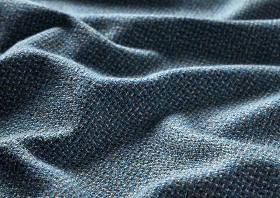 Textile showcasing Camira's Main Line Twist tweed, featuring a textured weave in blue and green hues.