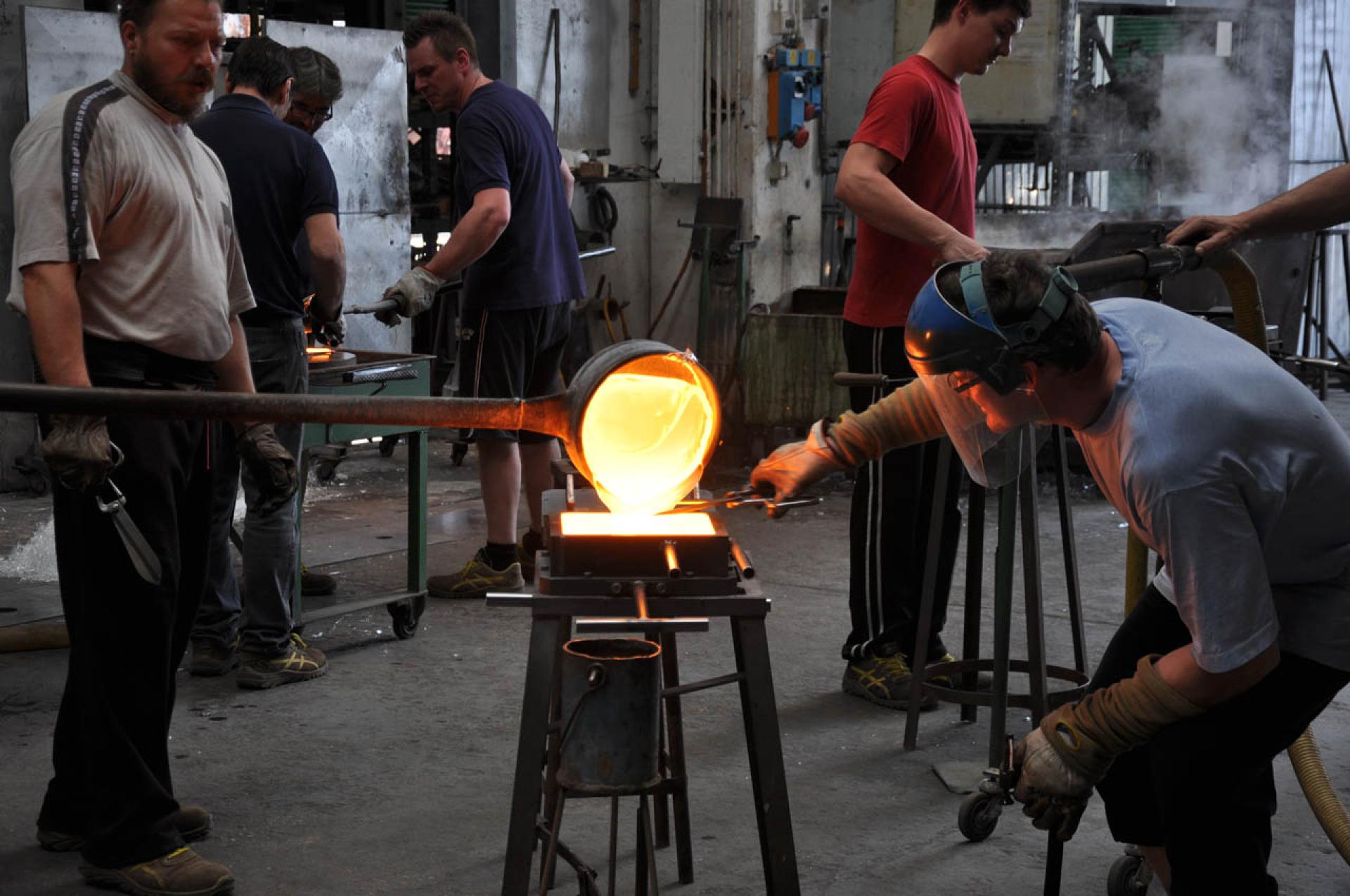 Craftsmen working in a glass studio, skillfully melting and shaping glass for MVRDV's Crystal Houses in Amsterdam.